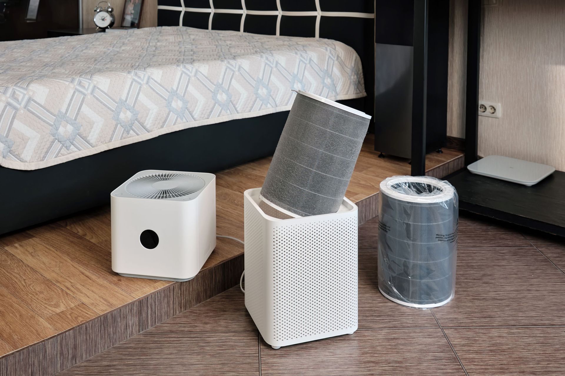 Air purifiers and filters on a bedroom floor.