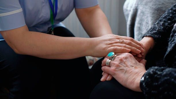 Caregiver holding hands with an elderly person, offering support.