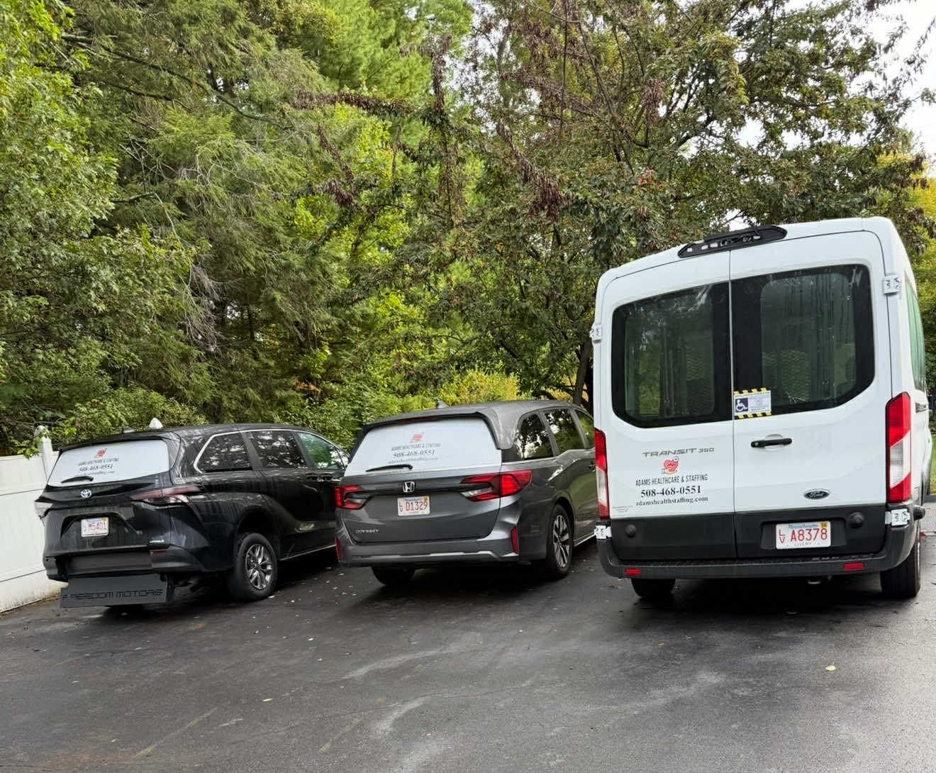 Three vehicles parked in a driveway: black SUV, gray SUV, and white van.