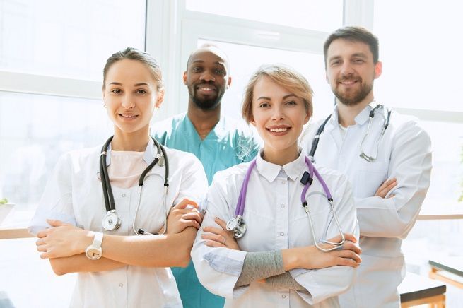 Group of medical professionals smiling, arms crossed, in a brightly lit room.
