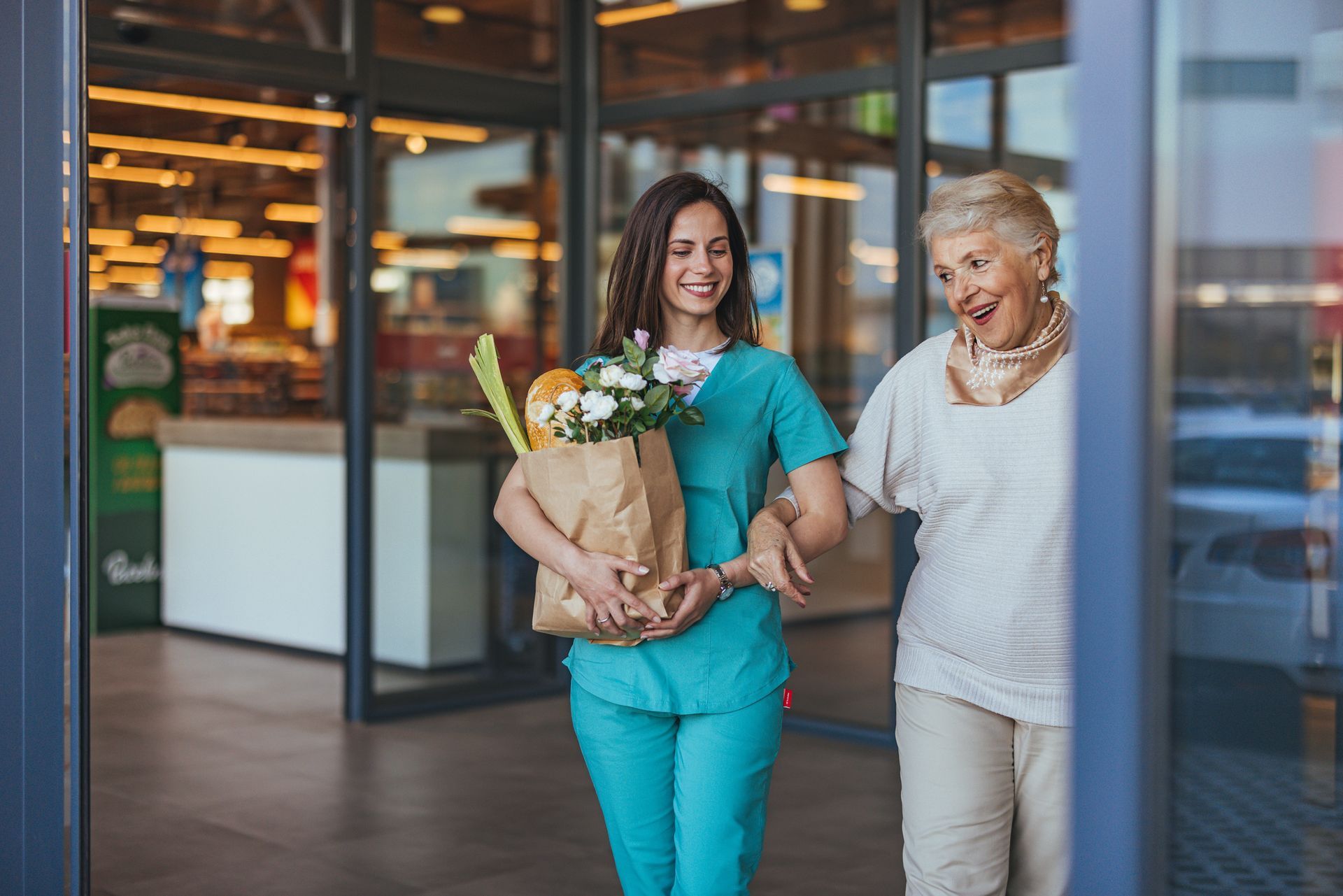Caregiver assisting senior with groceries, exiting a store.