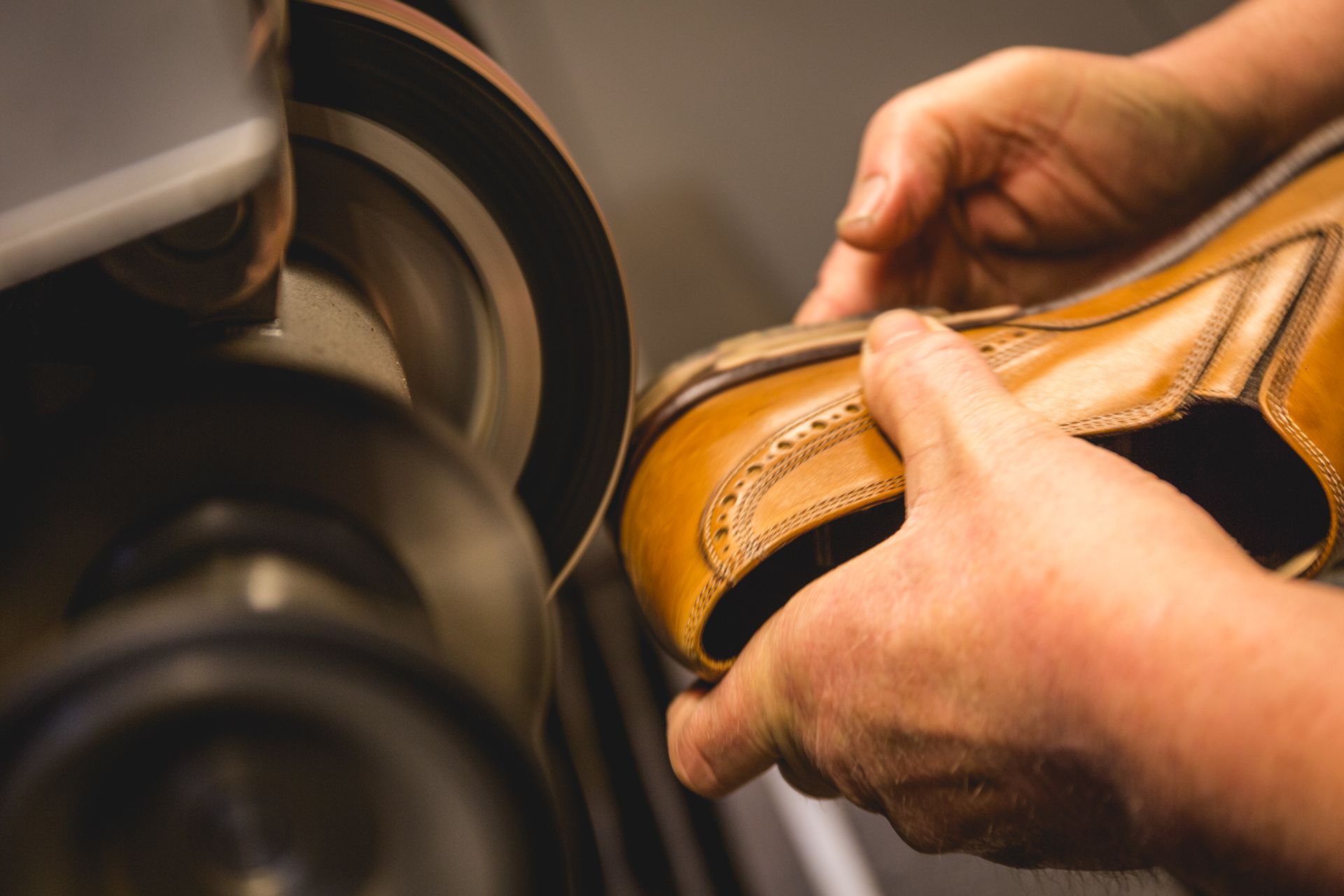 Schoenmaker gebruikt een machine om een ​​bruine leren schoen te poetsen.