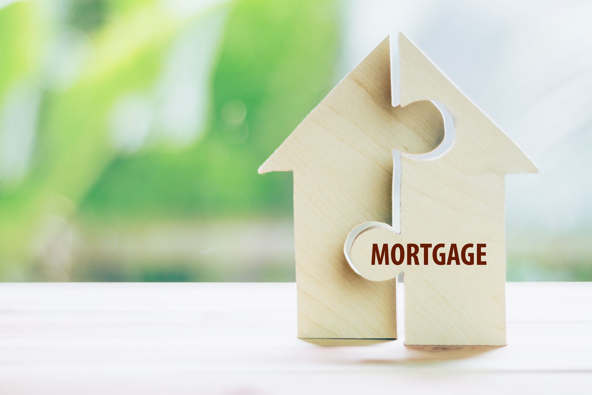 A wooden puzzle house with the word mortgage written on it.