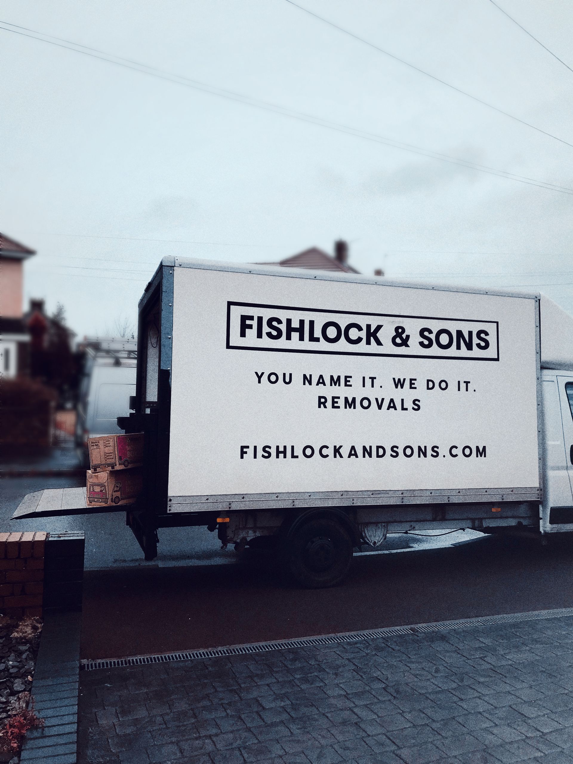 Moving truck for Fishlock & Sons parked on a residential street; text reads 