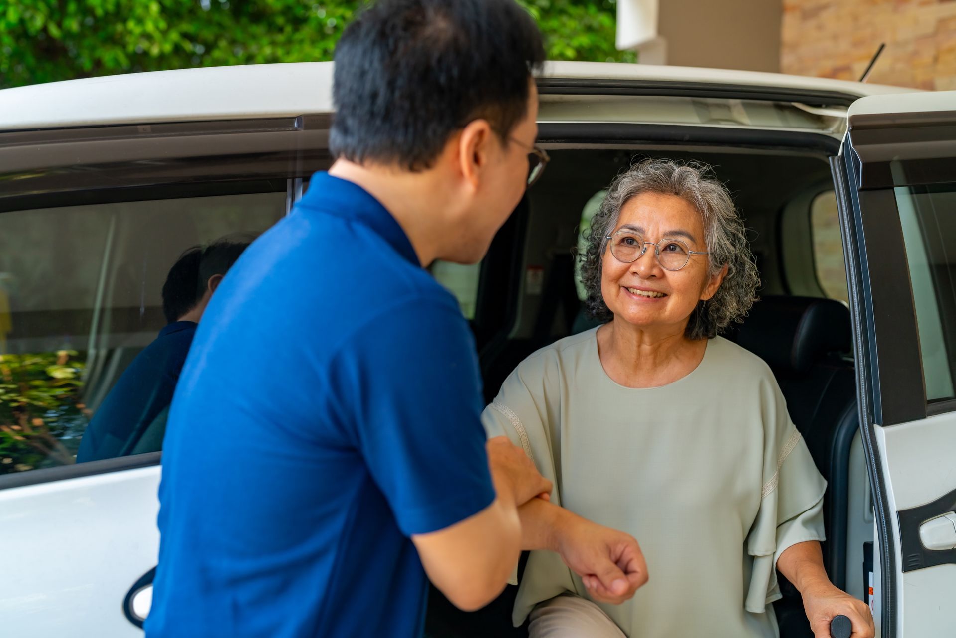 Caregiver helping a patient in a wheelchair enter a medical non-emergency vehicle