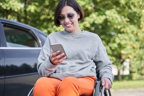 A woman in a wheelchair using her phone to schedule non-emergency medical transportation.