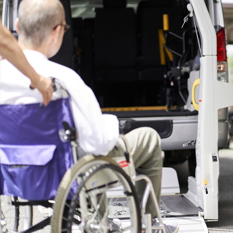 A senior man in a wheelchair is being assisted into a wheelchair-accessible medical transportation van using a lift for safe and reliable patient transport.