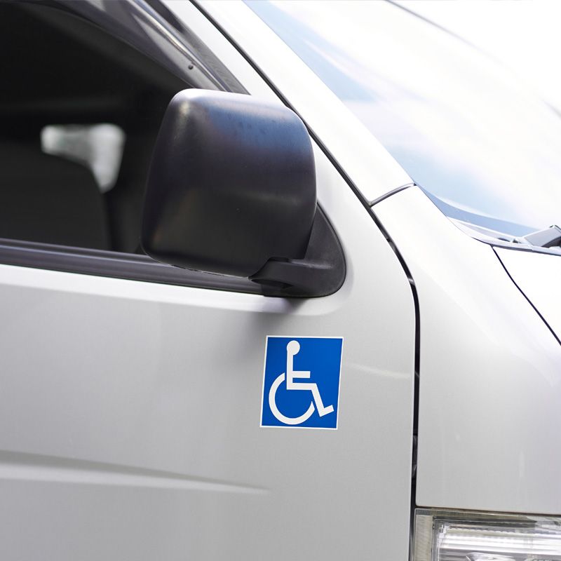 A wheelchair accessibility symbol is displayed on the side of a medical transportation vehicle, indicating handicap-accessible transport services.