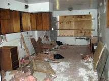 Kitchen in disrepair with exposed walls, cabinets, and debris on the floor.