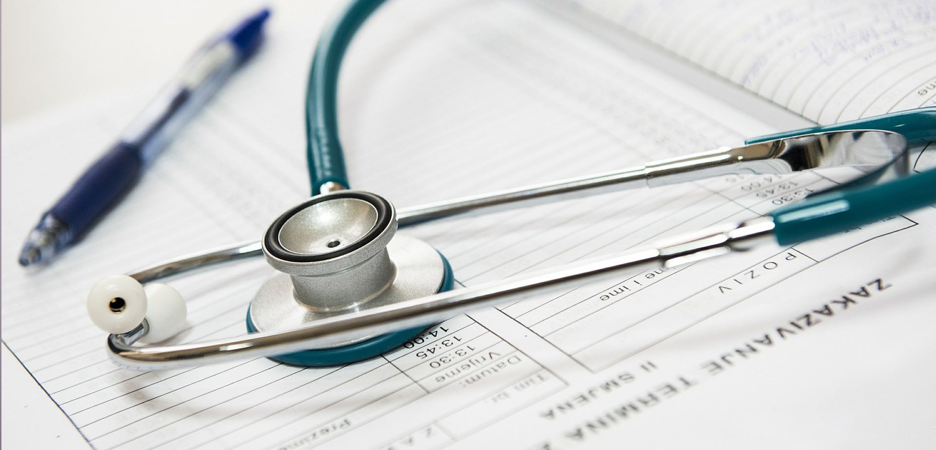 Stethoscope and pen rest on a medical form, suggesting a healthcare setting.