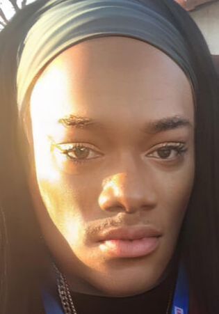Close-up of person wearing a dark headband and eyeliner, illuminated by sunlight.