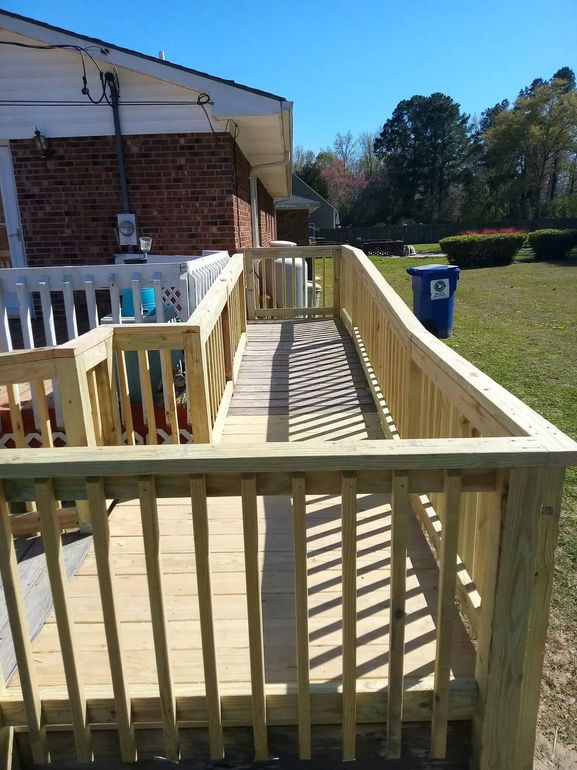 A wooden deck with a ramp leading to a house.