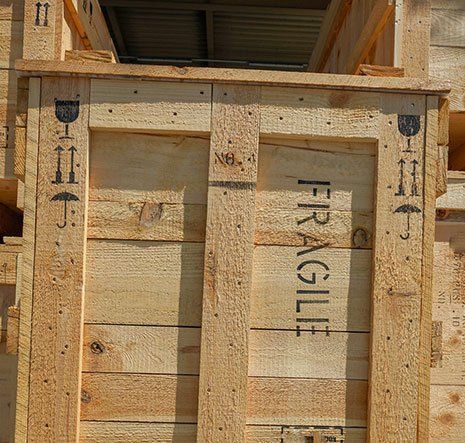 Wooden shipping crate with stenciled “FRAGILE” text and black handling symbols.