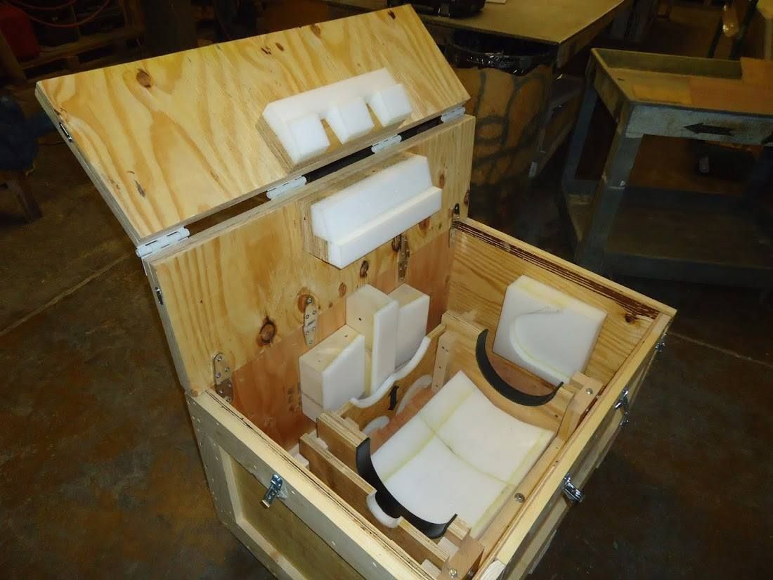 Open wooden box with foam inserts and white 3D-printed parts inside
