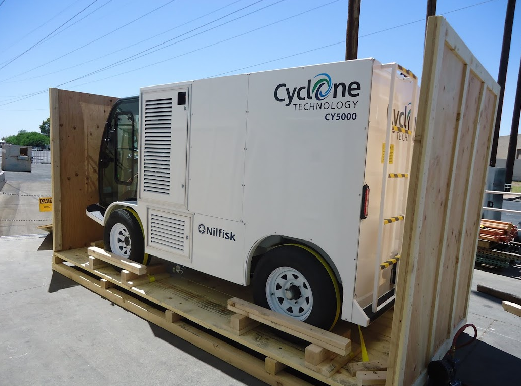 White Cyclone trailer-mounted machine on a wooden pallet in an industrial yard, viewed from the side