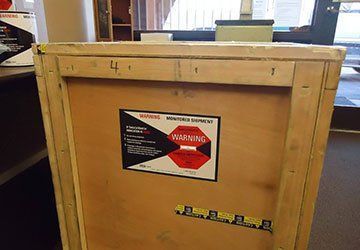 Wooden crate with a warning label in a warehouse or storage area.