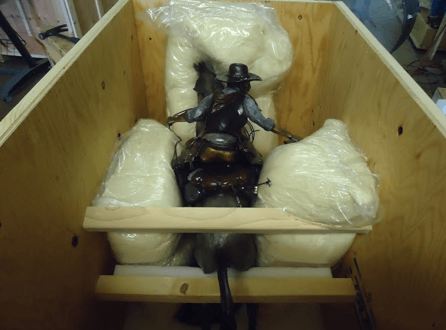 Black mannequin in a wooden crate, surrounded by padding and strapped in place