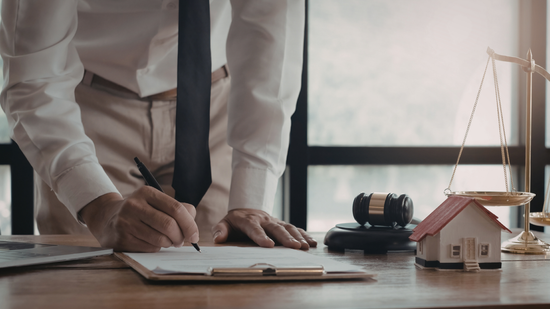 A professional headshot of a person with a friendly expression, wearing a dark suit and white collared shirt.