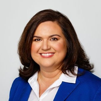 A man with a beard is wearing a blue suit and smiling