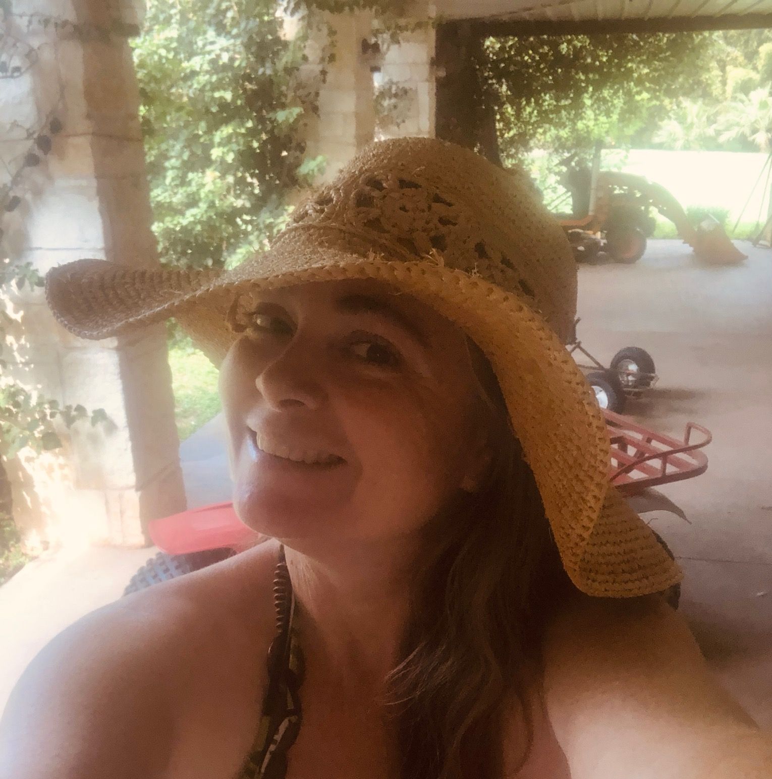 A woman wearing a straw hat is smiling for the camera
