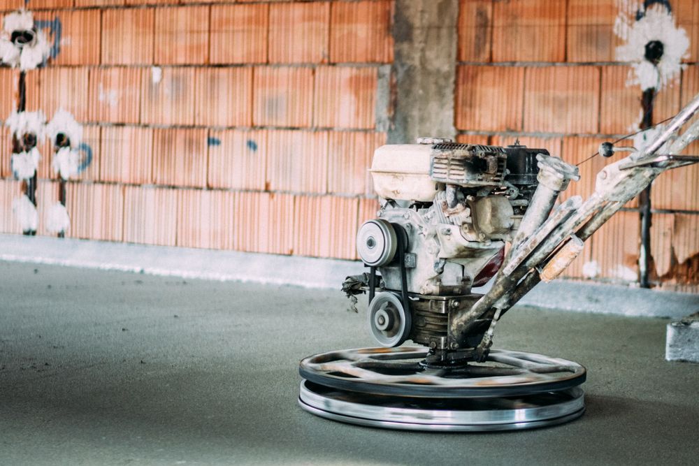Floor grinder in an unfinished room with orange wall insulation and concrete floor