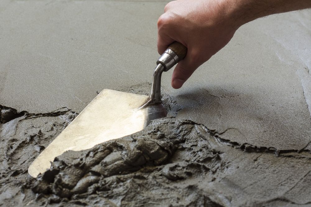 construction worker using hand trowel on a wet concrete floor