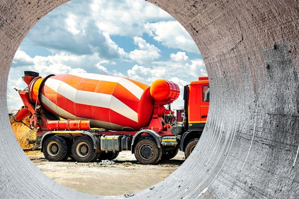 A concrete mixer truck is driving down a construction site.