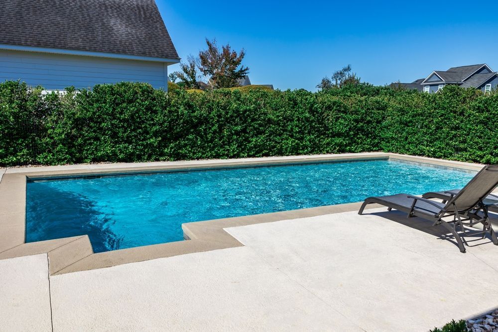 There is a large swimming pool in the backyard of a house.