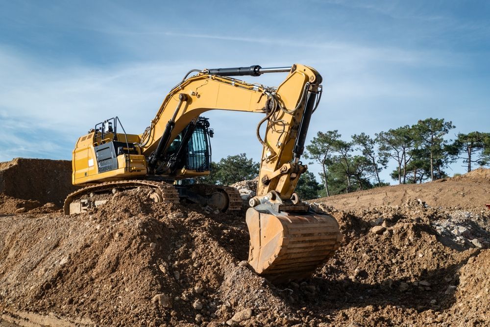 A yellow excavator is digging a hole in the dirt on a construction site.