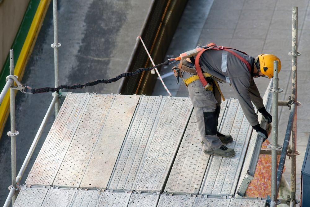 A man wearing a helmet is standing on a scaffolding.