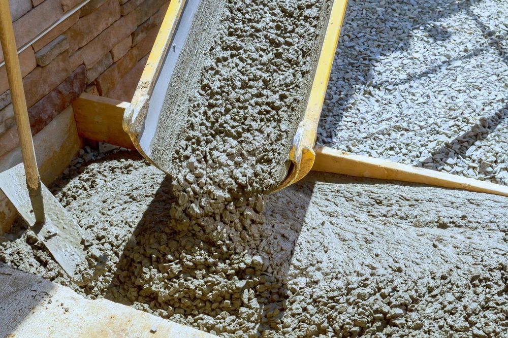 Concrete is being poured into a bucket with a shovel.