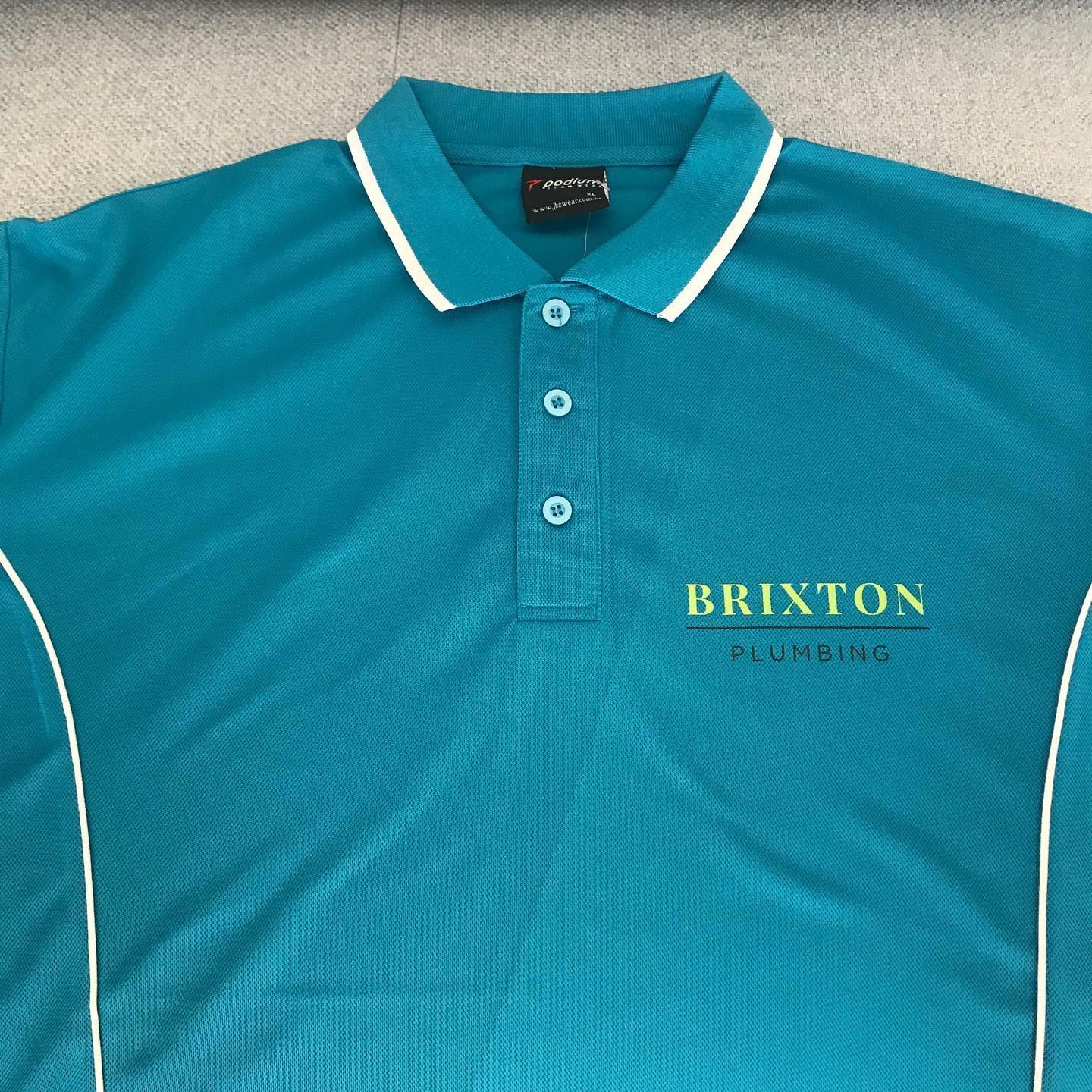 A blue shirt that says brixton plumbing on it