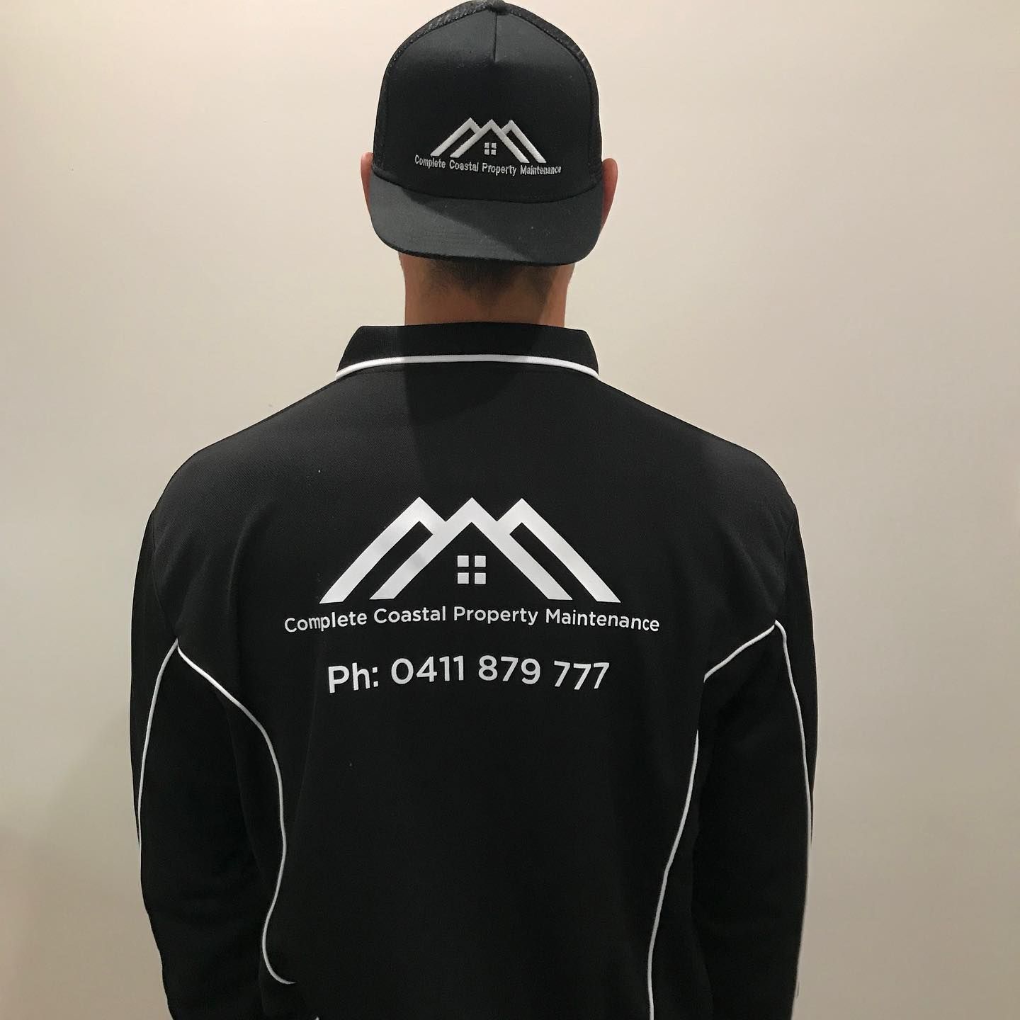A man wearing a hat and a jacket that says complete coastal property maintenance