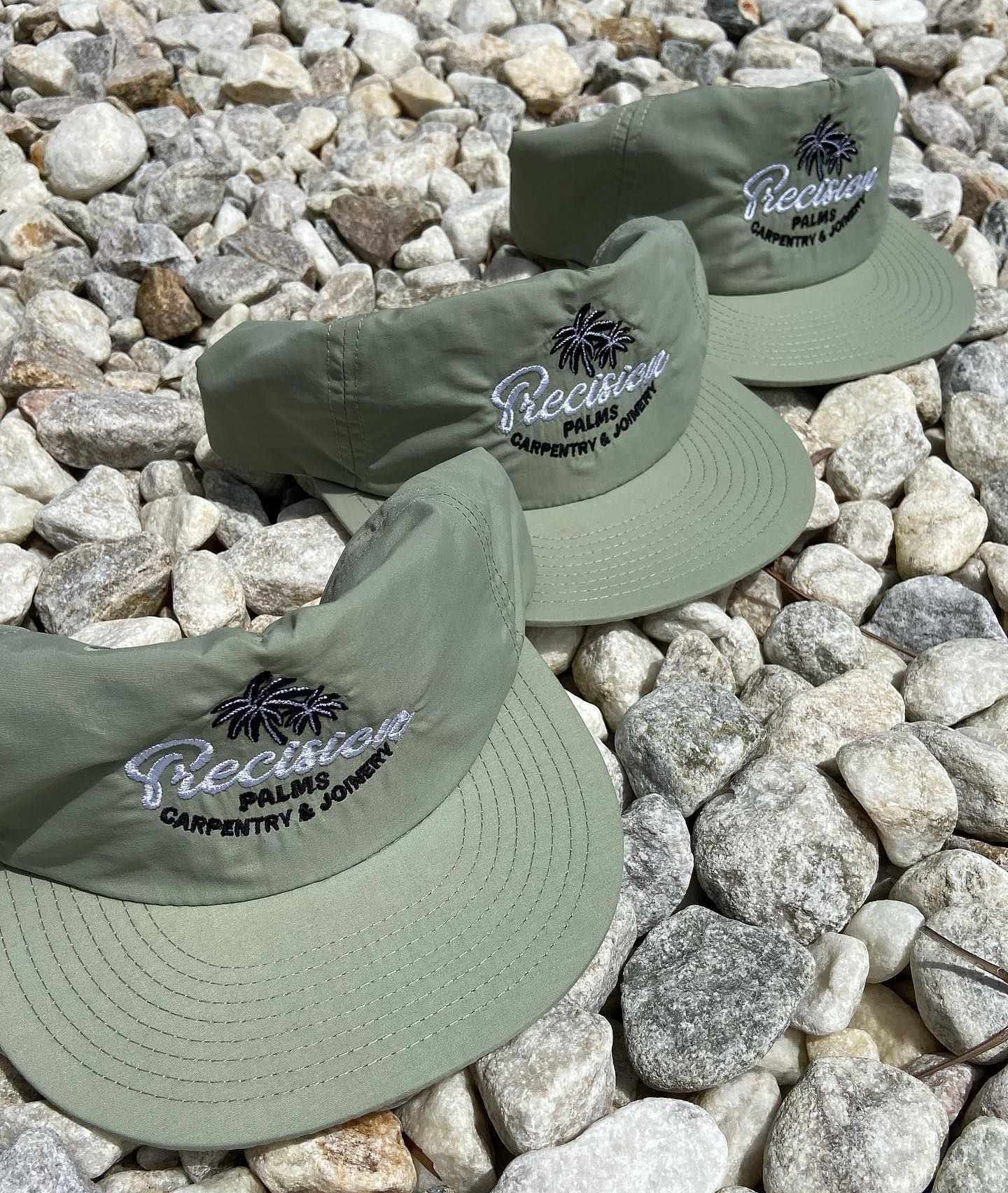 Three green precision hats are sitting on a pile of rocks