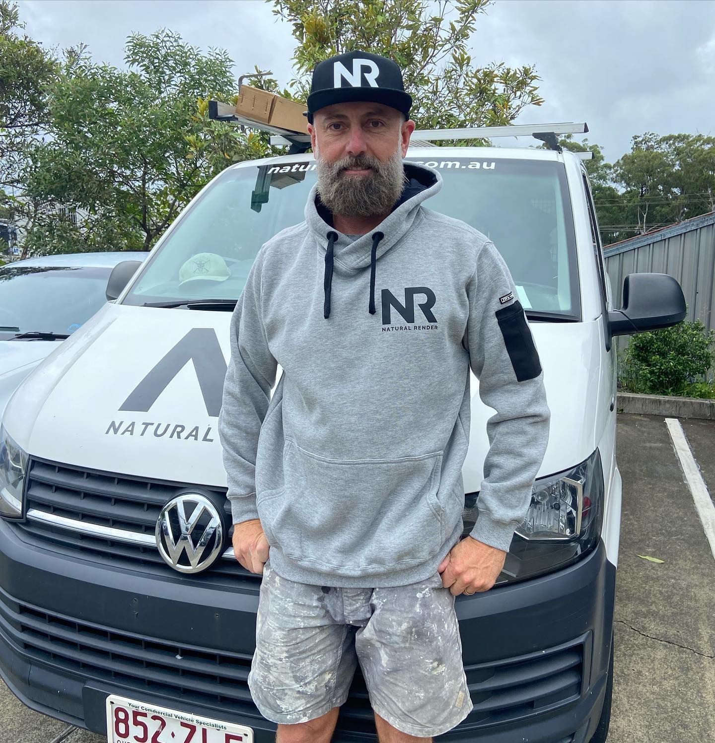 A man wearing a nr hat is standing in front of a van