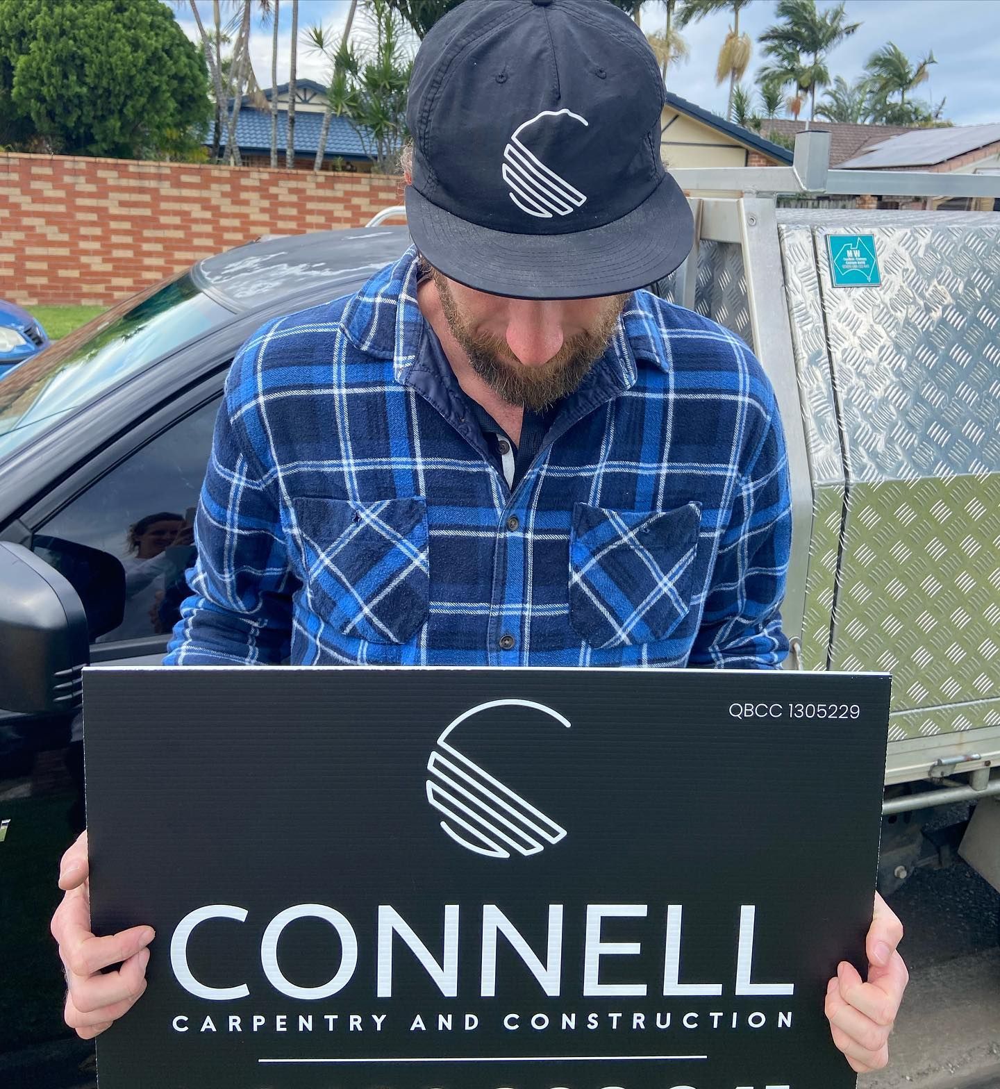A man holding a sign that says connell carpentry and construction