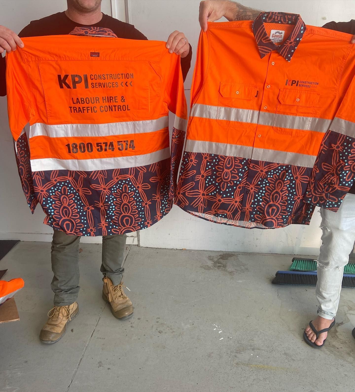 Two men are holding up orange shirts that say kpi