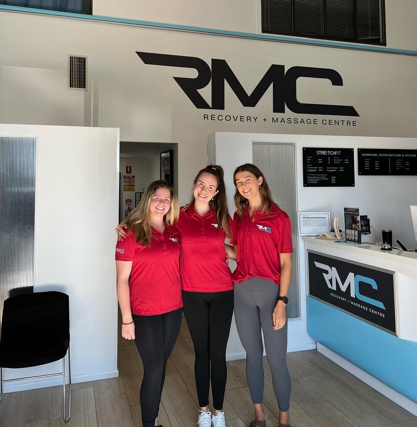 Three women standing in front of a rmc recovery massage center