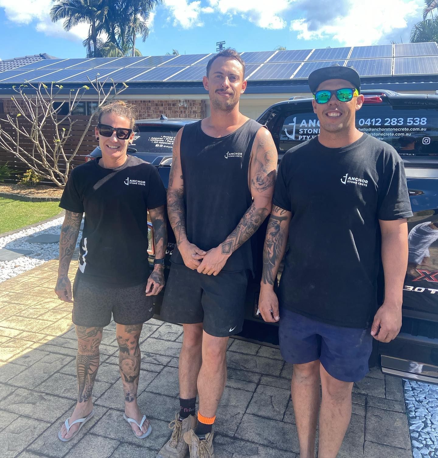 Three men are posing for a picture in front of a truck that has the number 0412 283 532 on the back