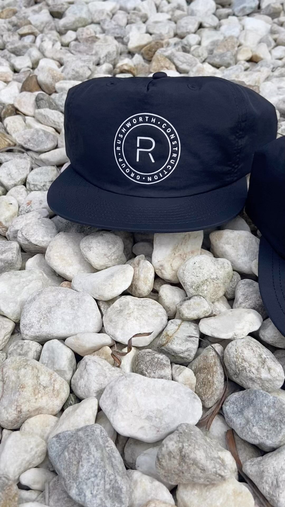 A black hat is sitting on top of a pile of rocks.