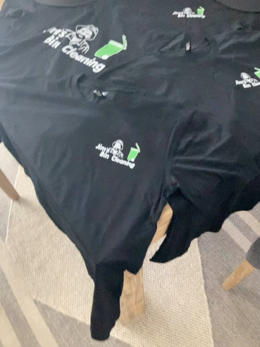 Two black t-shirts on a table that say mr. cleaning