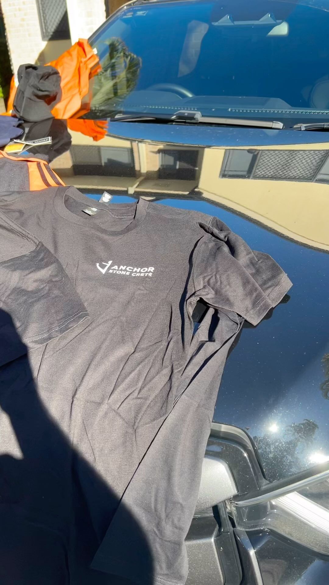 A person is holding a t-shirt over the hood of a car.