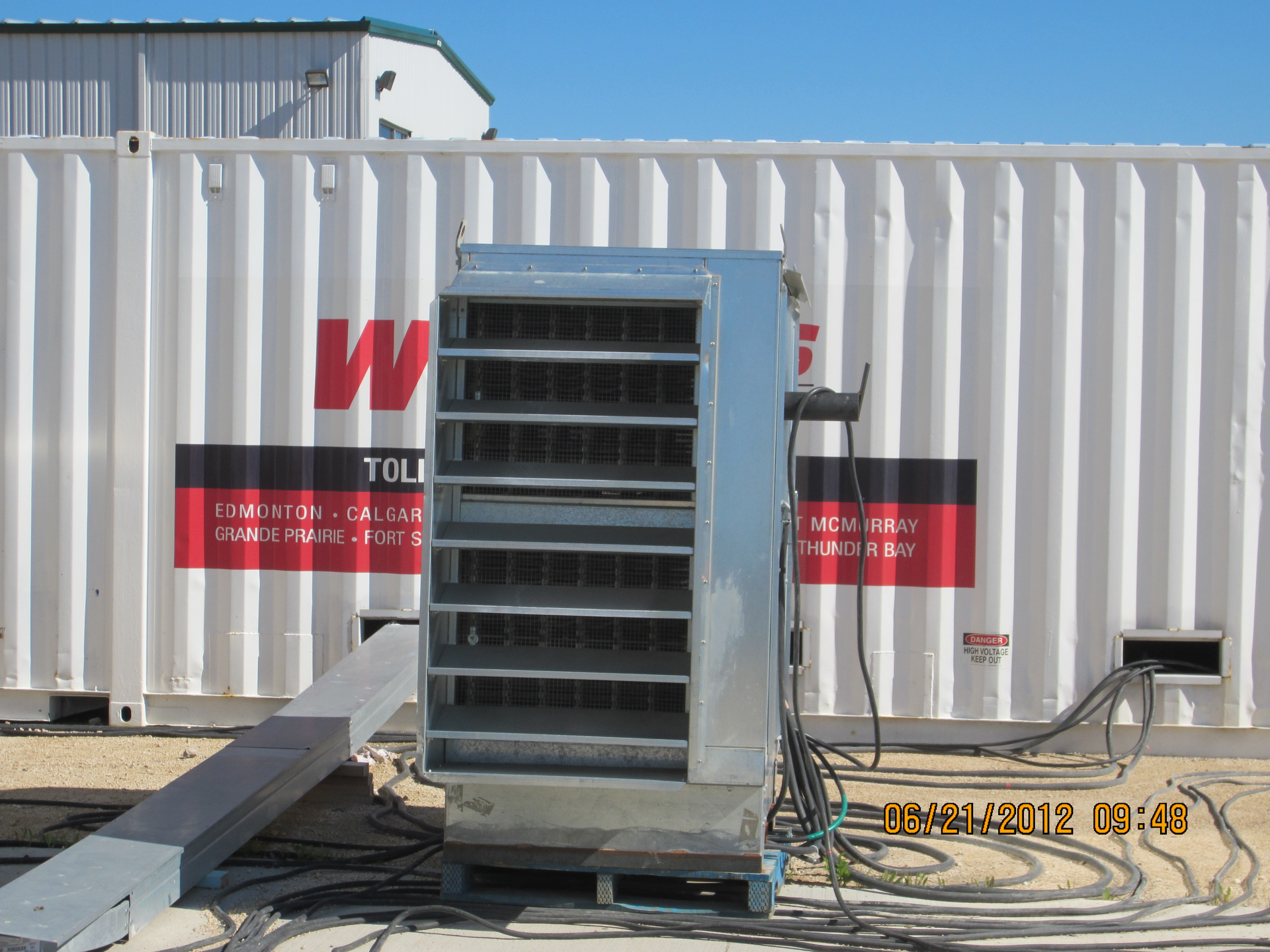 A person is checking the oil level of a generator with a screwdriver.