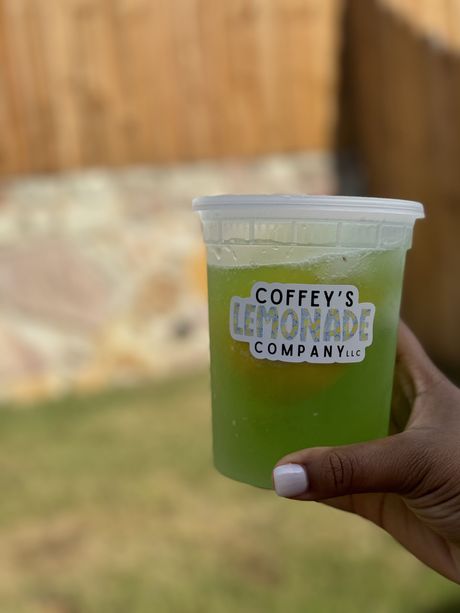 A person is holding a cup of coffey 's lemonade company lemonade