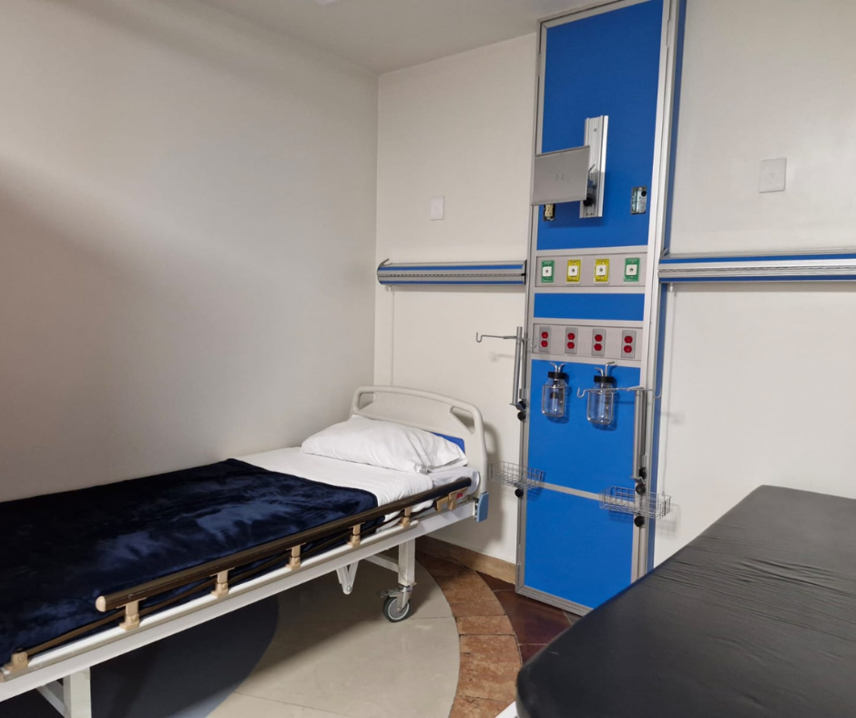 Habitación de hospital con cama, panel de equipo médico y mesa. Combinación de colores azul y blanco.