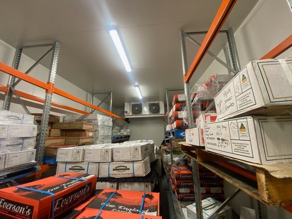 Interior of A Cold Storage Room Filled with Boxes Stacked on Metal Shelving  — Refrigeration & Air Conditioning in Jewells, NSW