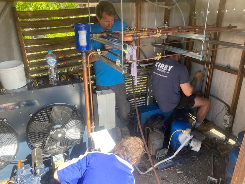 Three Men Installing Refrigeration Equipment Outdoors in a Shed — Refrigeration & Air Conditioning in Newcastle, NSW