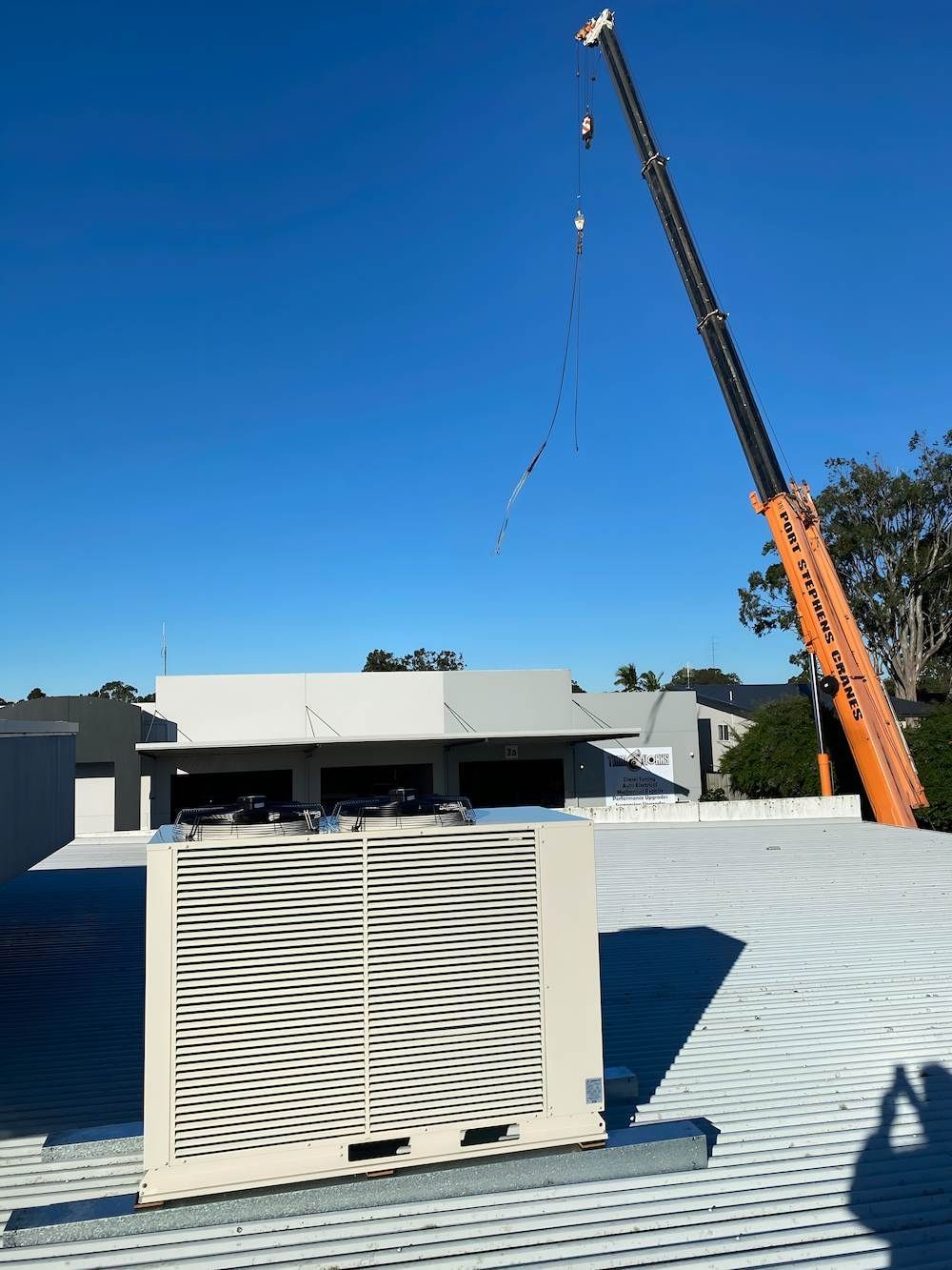 A Crane Lifting an Air Conditioning Unit Onto a Rooftop — Refrigeration & Air Conditioning in Hunter Valley, NSW