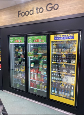 A grocery store with three refrigerators and a sign that says `` food to go ''.