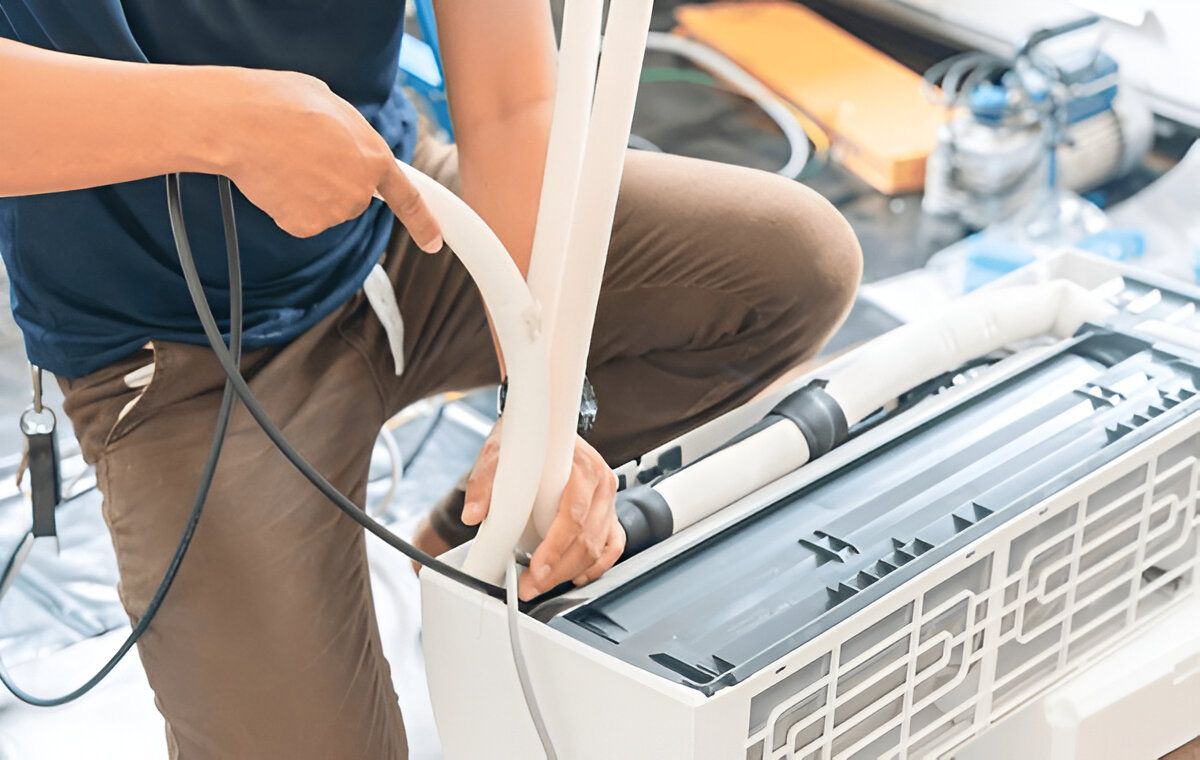 Person Installing Air Conditioner Unit, Holding Tubing and Wiring — Refrigeration & Air Conditioning in Maitland, NSW